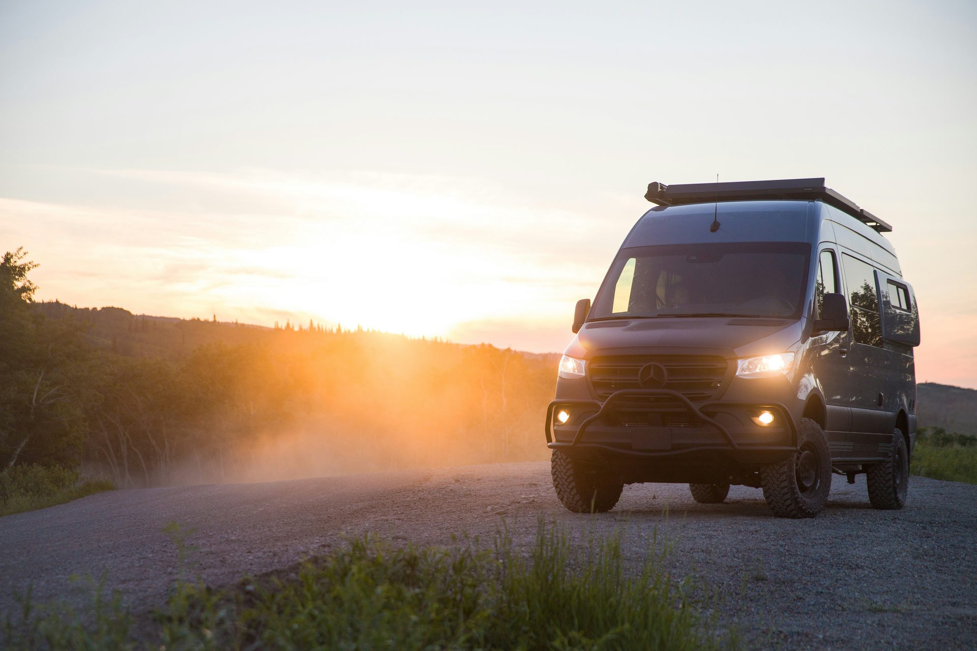 Sprinter 4x4 van on dirt road at sunset