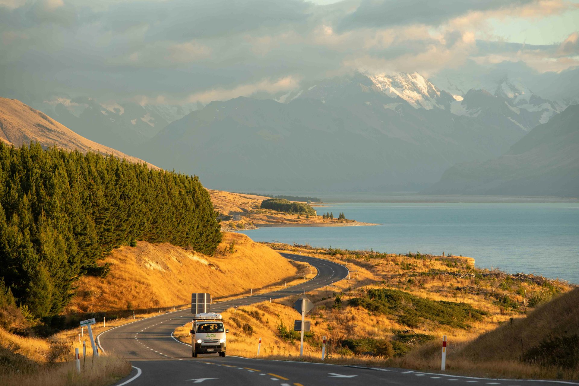 Camper van driving along a coastal highway with mountains